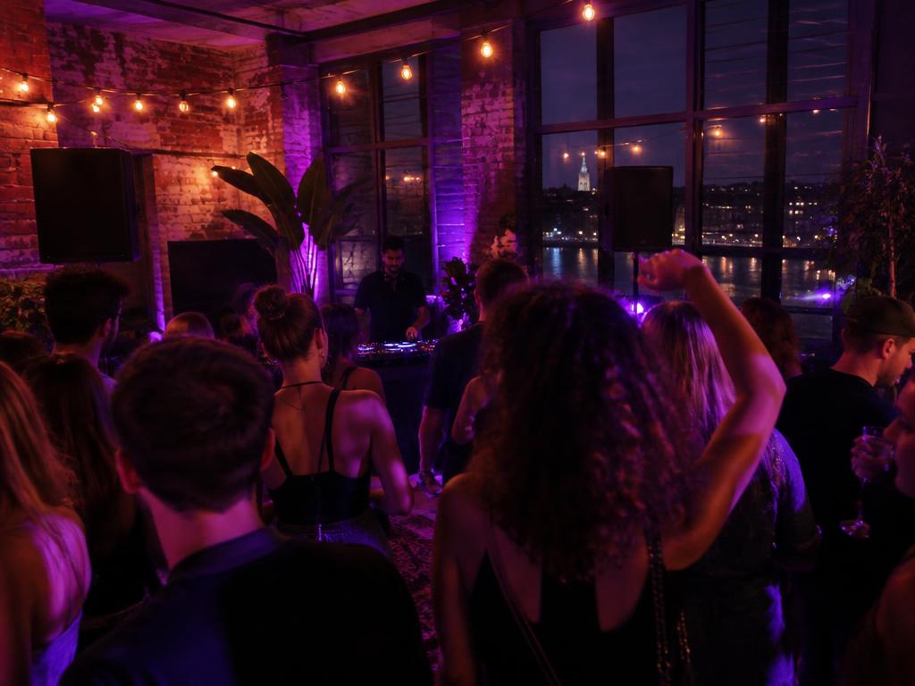 Intimate loft party at night with string lights, decks and a crowd dancing